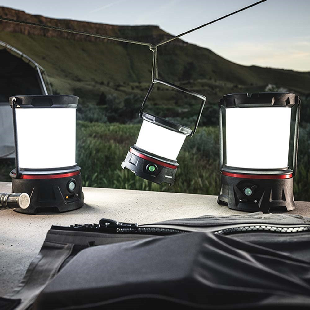 Coast EAL10R LED Lantern - Three camping lanterns on a table with a scenic background