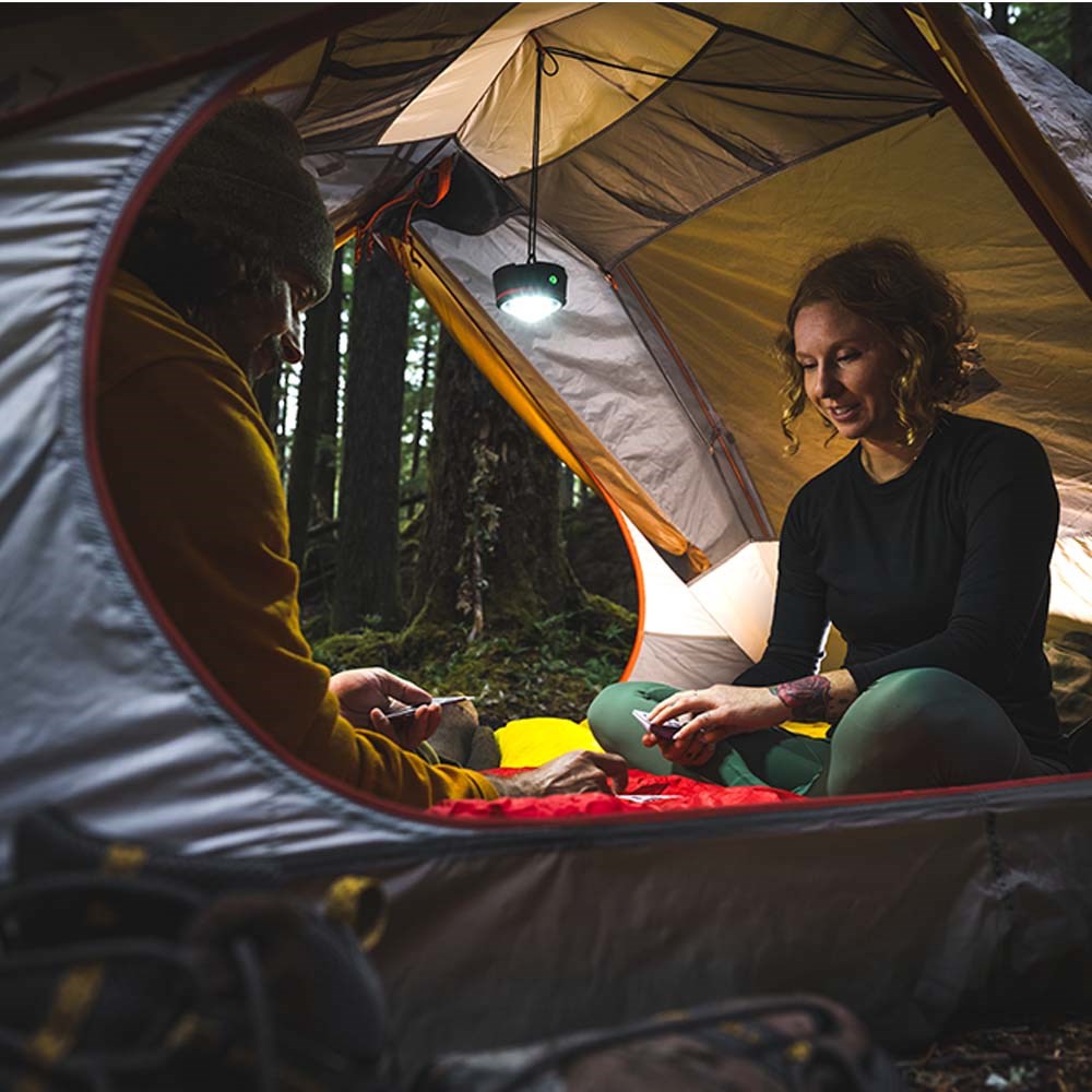 Coast EAL10R LED Lantern - Two people inside a tent in a forest setting with an LED Lantern