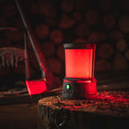 Coast EAL40R LED Lantern - Red lantern on a wooden stump with blurred logs in the background