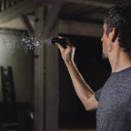 Coast XP11R LED Torch  - Person using a handheld device to spray water on a wall in a dimly lit room.
