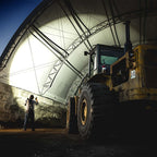 Coast XP80R LED Torch - lighting up a Large yellow bulldozer under a large white tent-like structure with a person standing nearby.