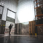 Coast XP80R LED Torch - Person working in a large warehouse with high ceilings and industrial equipment.