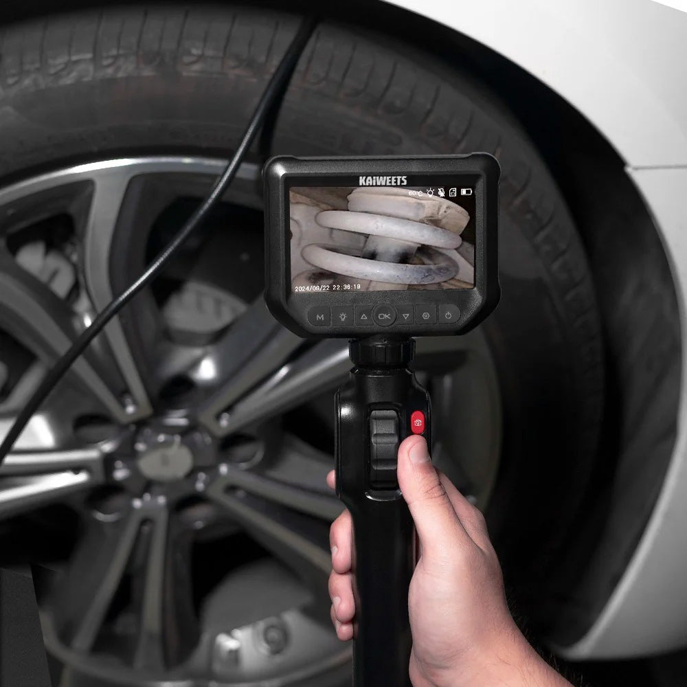 Hand holding a digital inspection camera in front of a car tire